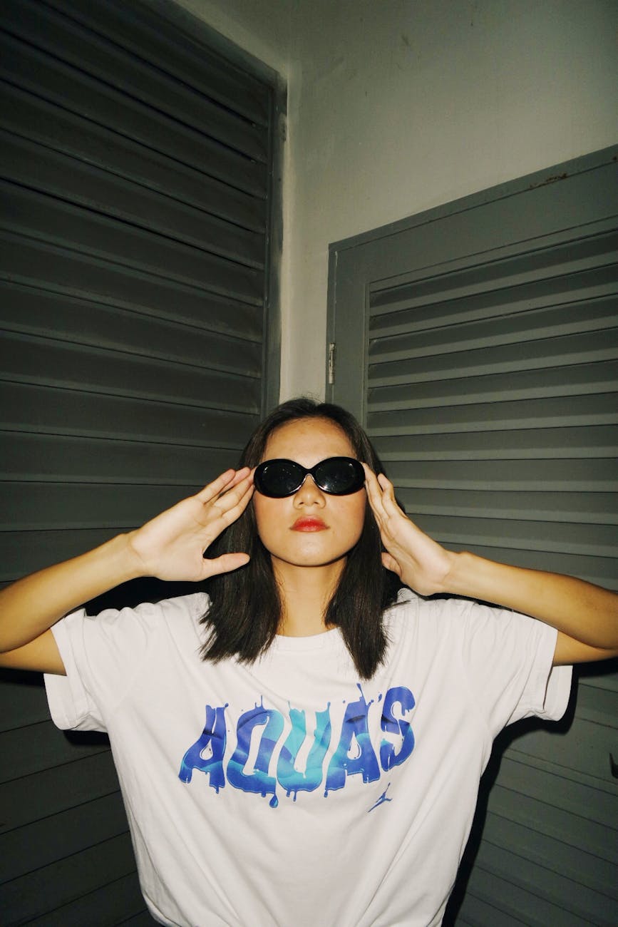 woman wearing a white t-shirt merch and black framed sunglasses